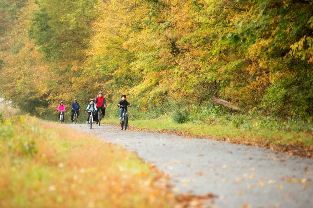 adults and children riding bikes on the mcdade trail in fall