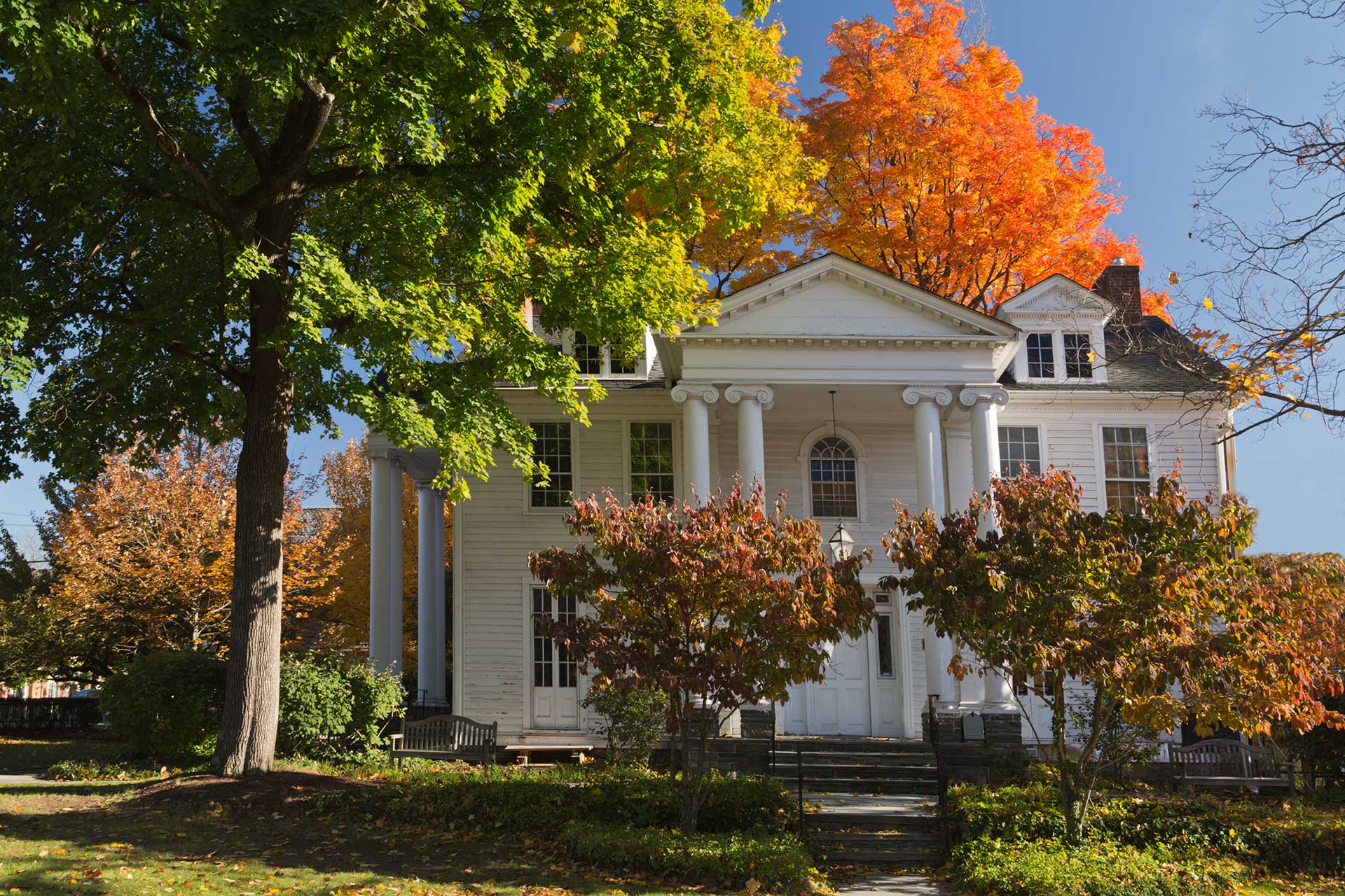 the large white community house surrounded by fall trees